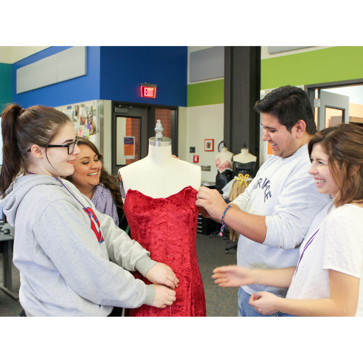 A group of people looking at a dress on a mannequin.