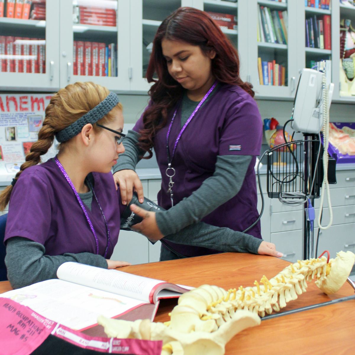 A woman in purple is helping another woman in a lab.